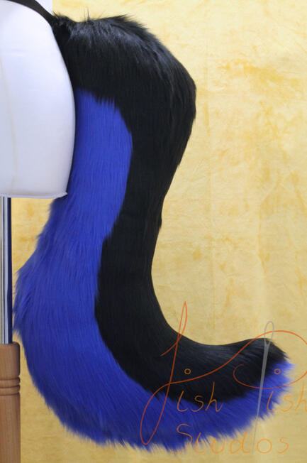 A larger 25 inch long drop wolf tail which attaches to a belt using belt loops. It is made from luxury faux fur, this one it two colours with the top being black and the the base or underside being a royal blue. It is handmade in the UK by FishPish Studios
