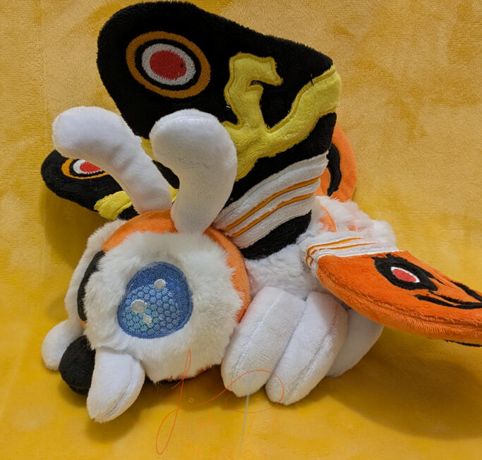 a handmade, highly detailed mothra plushie. This design comprises of applique, hand sewn parts, various fabrics and a very cute face. Made by fishpish studios in the UK