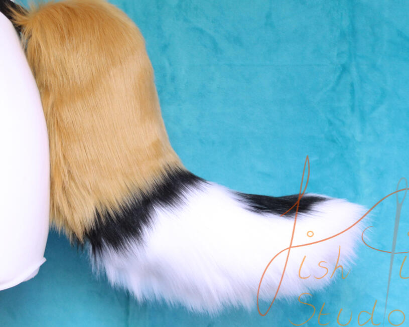 A caramel, white and black designed wild dog tail. It's approx 16 inches long and attaches with belt loops at the base. handmade in the UK by fishpish studios