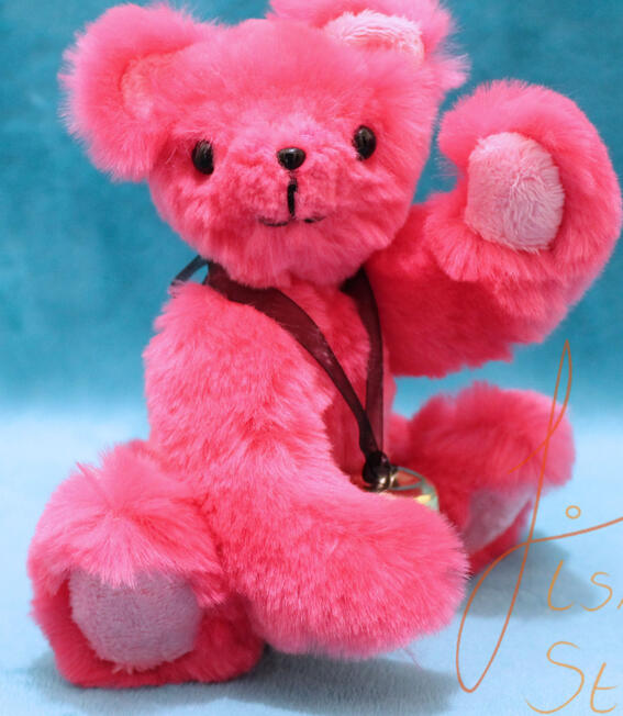 A small, cute, pink jointed teddy bear a little pink jointed teddy bear waving hello. it has a bell around it's neck. Made of faux fur and minky fabrics