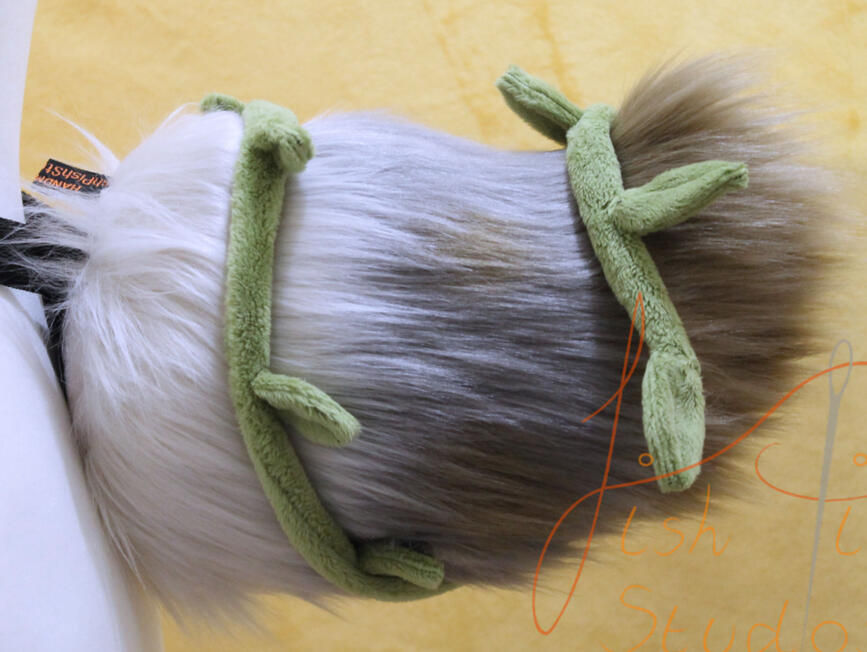 A custom made faux fur deer tail with removeable leaves and vine. This was made as a competition prize on Bluesky. It is made from various shades of creams and brown faux furs, with a green, wire cored vine wrapped around it. designed by the winner and mad