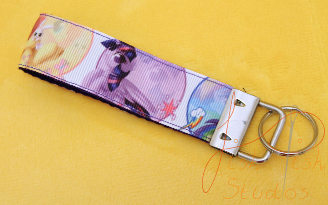 My Little Pony Themed Key Fob Keyring a cute photo showing a my little pony themed keyring made of fabric. It has little artwork of the mane size ponies including twilight sparkle, rarity and rainbowdash. handmade in the UK by fishpish studios
