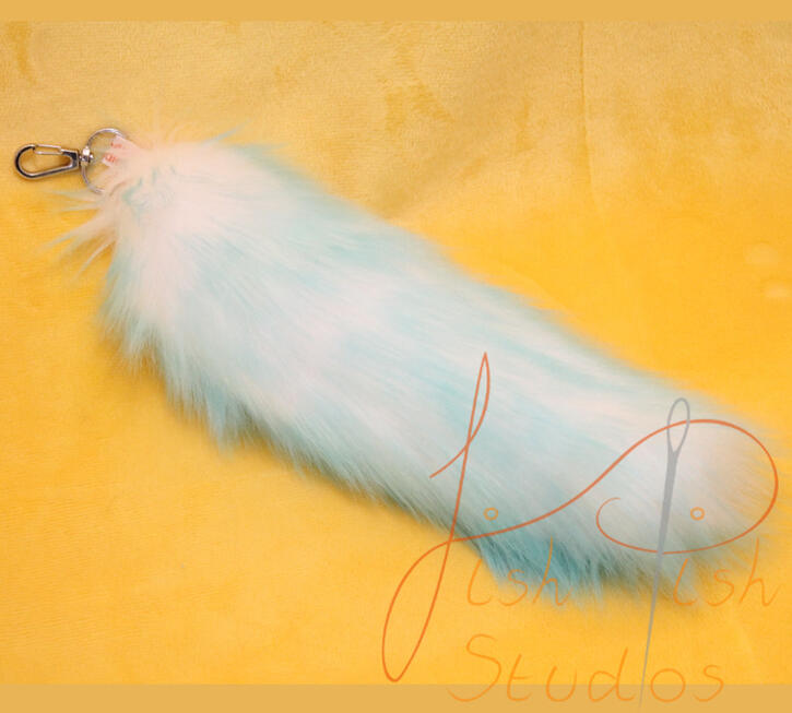 Aqua and White Fade Bag Tail a photo showing a fox styled tail in aqua with a white fade laying on a yellow table. these bag tails are about 9 inches long, and attach to bags or clothing using clips. handmade in the UK by fishpish studios with luxury faux fur